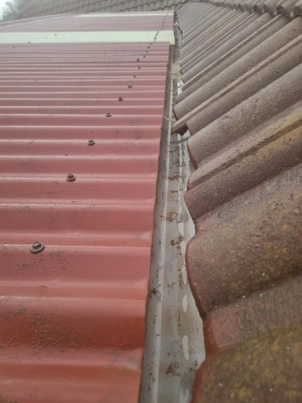 A clear corrugated-roof gutter after debris removal