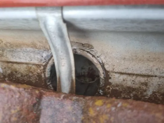 Close-up of a downpipe outlet clogged with rust and debris