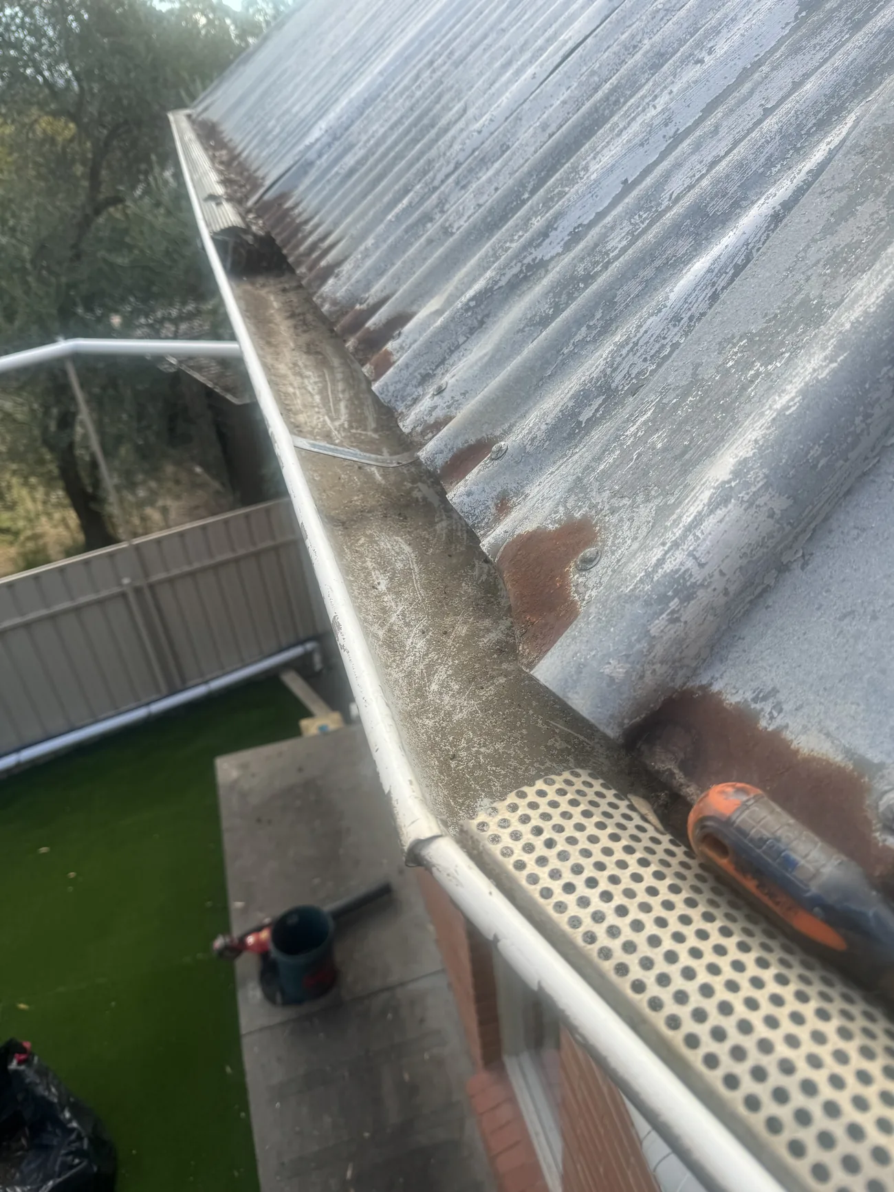 Clearing built-up debris from a corrugated-roof gutter during a job